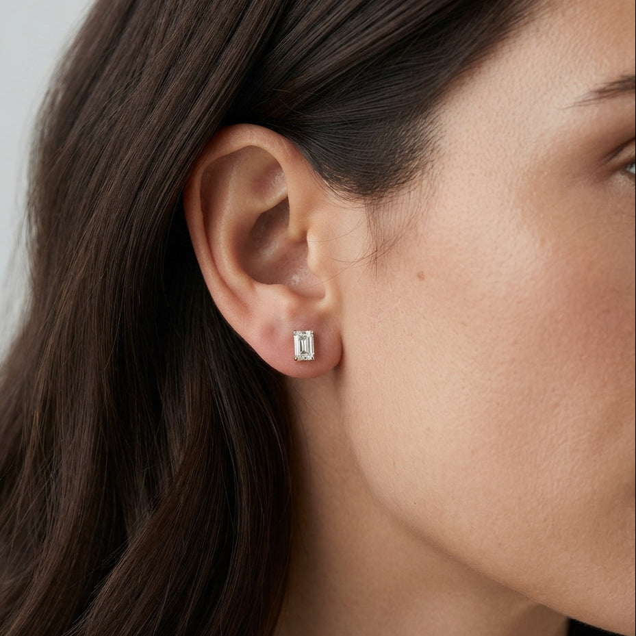 emerald diamond stud earrings on a girl earlobe