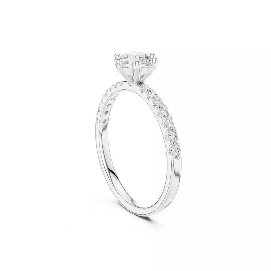 A white gold diamond engagement ring with a round-cut center stone and a pavé band, shown on a clean white background.