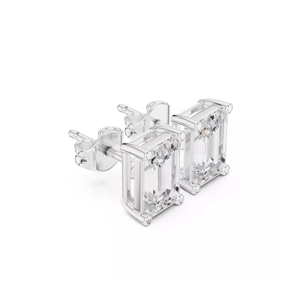A pair of silver stud earrings featuring rectangular emerald-cut clear gemstones in a prong setting, shown on a plain white background.