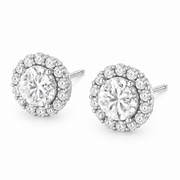 A pair of round halo stud earrings featuring a large clear center stone surrounded by a halo of smaller clear stones, set in 14k gold  on a plain white background.